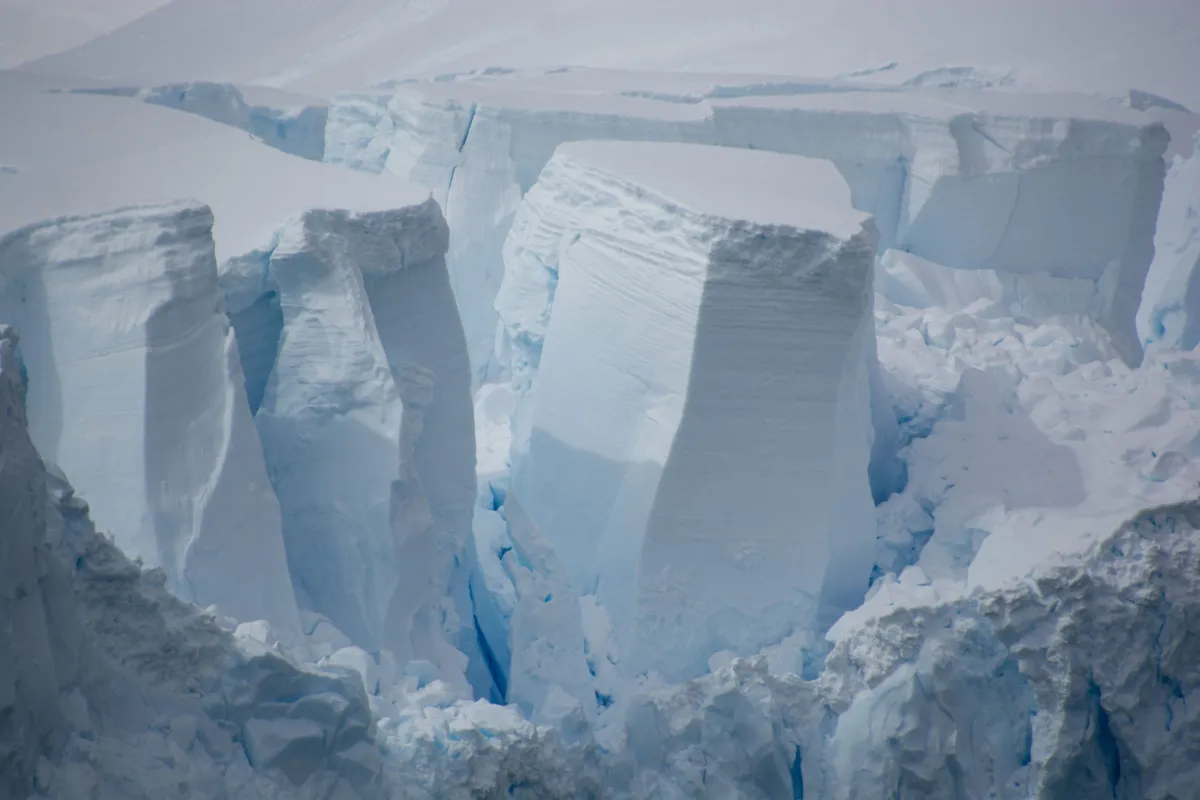 Large, dramatic ice formation with deep crevices and towering ice blocks in polar region.