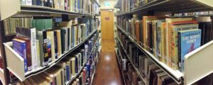 Library aisle with bookshelves and wooden door.