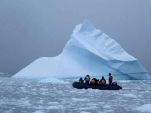 Group in an inflatable boat with iceberg background, Antarctica.