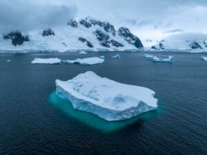 Iceberg floating with snow-covered mountains in the background, Antarctic waters.